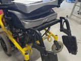 yellow wheel chair with black seat and foot rests in a warehouse