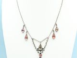 a necklace with a cross and pink stones on a mannequin