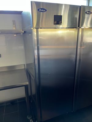 un réfrigérateur en acier inoxydable dans une cuisine, à côté d'une étagère