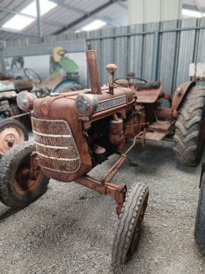 un tracteur rouillé garé dans un garage avec d'autres véhicules