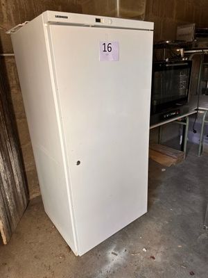 un réfrigérateur blanc posé dans un entrepôt, avec une étiquette de prix dessus
