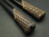 pair of black and gold chopsticks sitting on a black surface