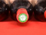 four bottles of wine are lined up on a red surface