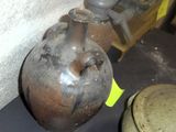 un grand vase en métal posé sur une table, à côté d'autres objets