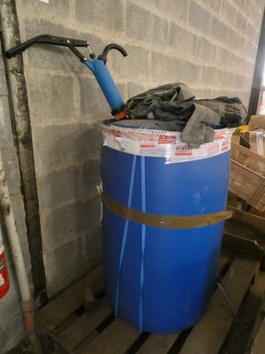 un fût bleu posé sur une palette à côté d'un mur de briques