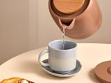 a person pouring tea into a cup on a table