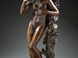 a bronze statue of a woman leaning against a tree