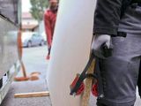 a man holding a white surfboard on the street