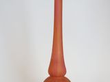 un vase rouge posé sur une surface blanche
