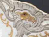 an image of a close up of a white and gold plate with a bird on it