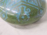 a green and blue vase sitting on a white surface
