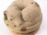 un beignet posé sur une assiette en bois, sur une surface blanche