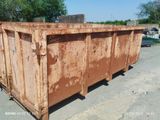 une benne à ordures rouillée abandonnée sur un parking