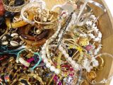 a wooden bowl filled with lots of jewelry on a table