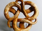 a sculpture of a knot made of wood on a clear stand
