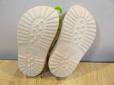 pair of children ' s white and green tennis shoes on a wooden surface