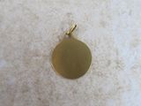 a close up of a gold plated pendant on a white surface