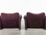 two purple chairs sitting next to each other in a room