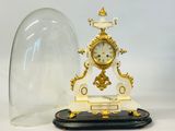 une petite horloge sous un dôme de verre sur une table