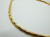 a close up of a gold necklace on a white surface