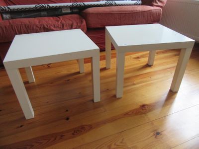 deux tables blanches posées sur un parquet dans un salon