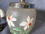 a glass jar with flowers painted on it next to a plate