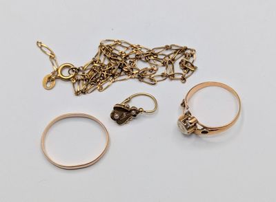 two gold rings, a chain, and a ring on a white surface