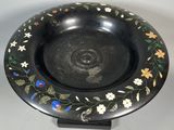 an image of a black plate with flowers and leaves painted on it