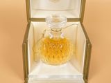 an open box with a perfume bottle inside of it on a beige surface