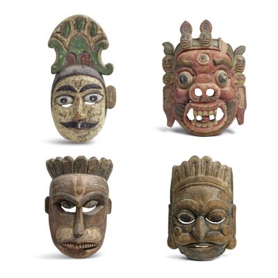 quatre masques en bois de formes et de tailles différentes sur un fond blanc