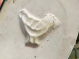 a close up of a person ' s hand holding a white plate with a bird on it