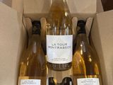 trois bouteilles de vin blanc dans une boîte en carton posée sur une table