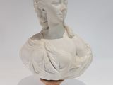 marble bust of a woman with braids on a wooden base