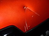 a close up of a red car with a broken hood
