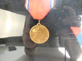 une médaille d'or ornée d'un ruban rouge, blanc et bleu