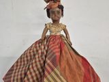 a close up of a doll wearing a dress and hat