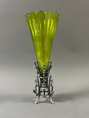 une image représentant un vase vert posé sur un socle métallique