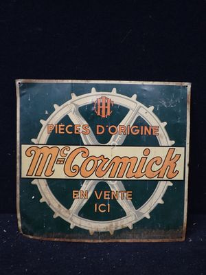 une vieille enseigne métallique faisant la promotion des cigarettes McCormick sur fond noir