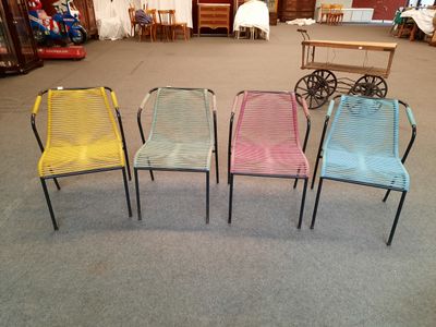 quatre chaises alignées dans une pièce, avec une table et des chaises en arrière-plan