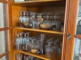 a wooden cabinet with many glasses and plates on it