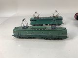 two green trains sitting on a white surface