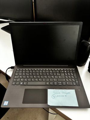 un ordinateur portable posé sur un bureau, sur lequel se trouve une note