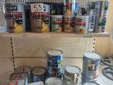 many cans of paint sitting on a shelf in a kitchen