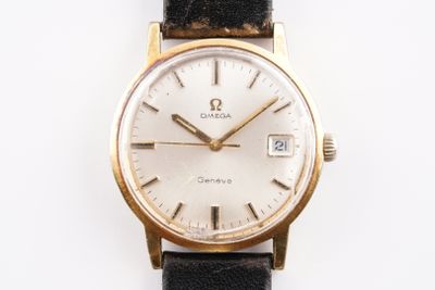 a gold watch with a white dial on a black strap