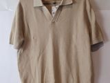 beige sweater hanging on a hanger on a wall in front of a white wall