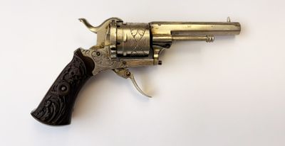 un vieux revolver avec une poignée en bois sur une surface blanche
