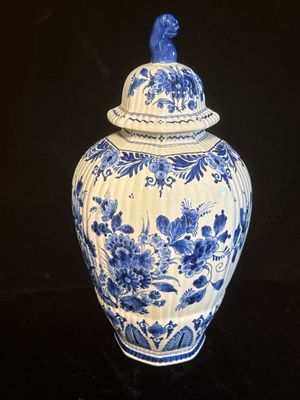 un vase bleu et blanc surmonté d'un oiseau