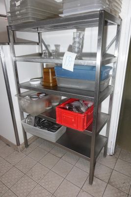 une étagère métallique sur laquelle sont posés de nombreux objets, dans la cuisine