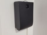 a black paper towel dispenser hanging on the wall