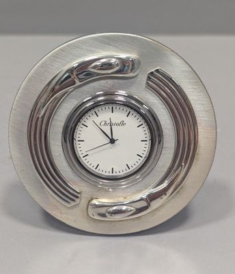 silver clock sitting on a table with a snake on it ' s face